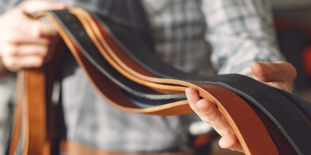 Man working with leather. Professional makes a belts.